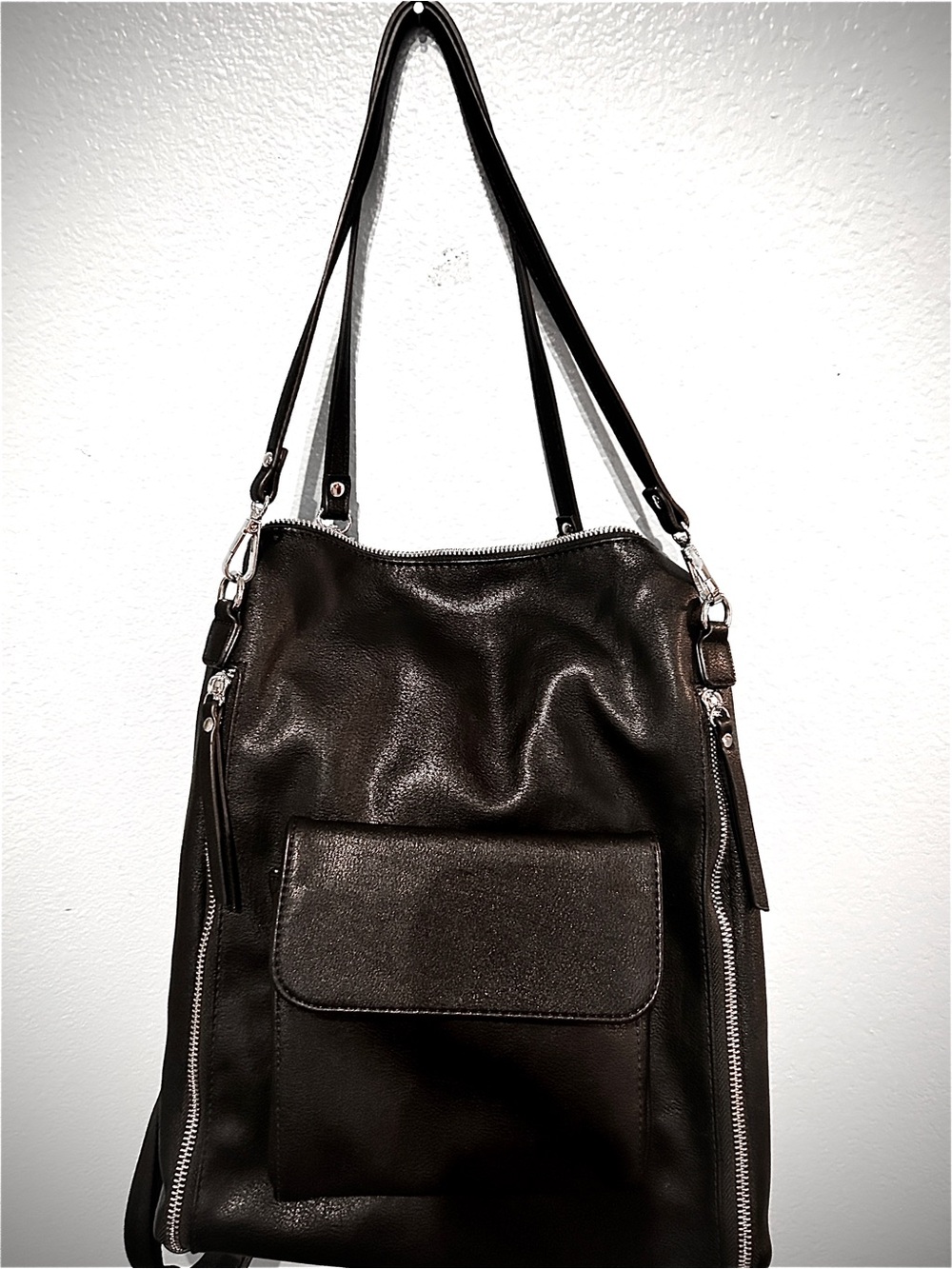 Soft black faux leather convertible backpack with vertical side zippers and flap